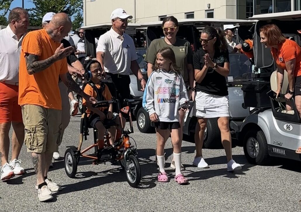 Angelo Murphy rides his new adaptive bike at the 2026 Flyers Charity Weekend Classic with Kelly L Green.
