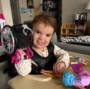 3-year-old Ellie Cooper holds up a Barbie wheelchair.