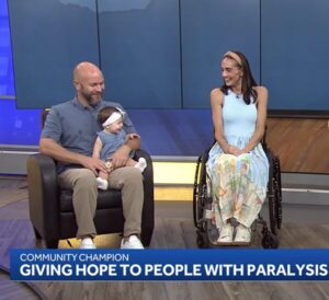 Amanda Perla in her manual wheelchair with baby Scottie and her husband on WESH 2 in Central Florida in 2026.