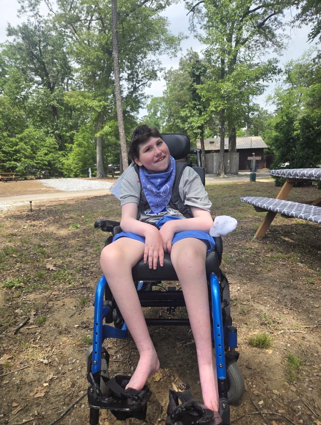 Teen Nick Lovecchio is seated outdoors in a manual wheelchair.