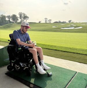 Help Hope Live client Lucas Towers participates in adaptive golf with AdapTee from his power chair in August 2026.
