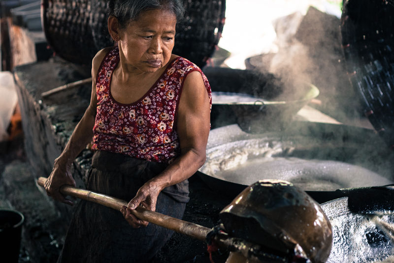 Old Thai woman making coconut sugar in Amphawa District
