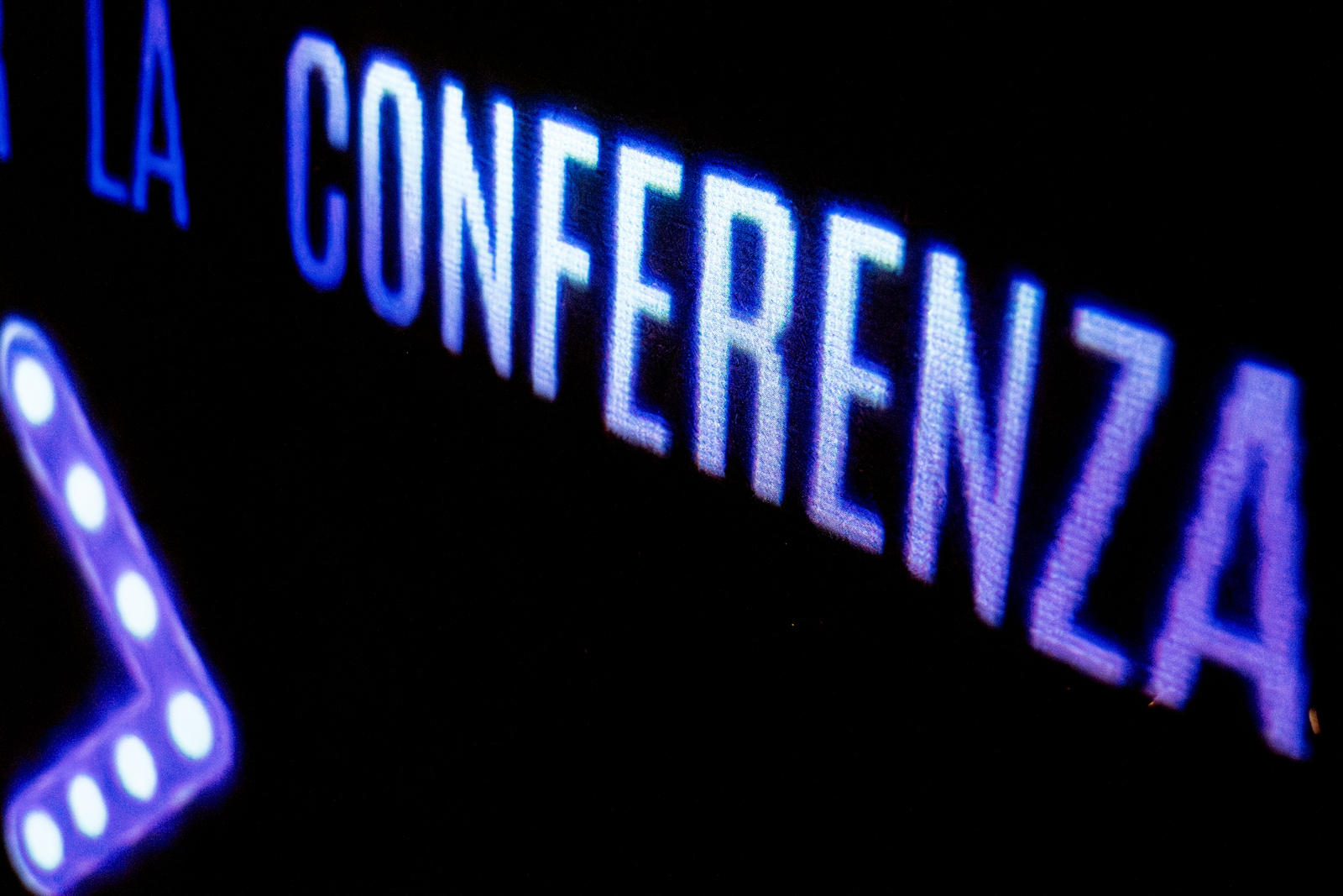 Segnaletica proiettata in blu, con la scritta “la conferenza” e una freccia