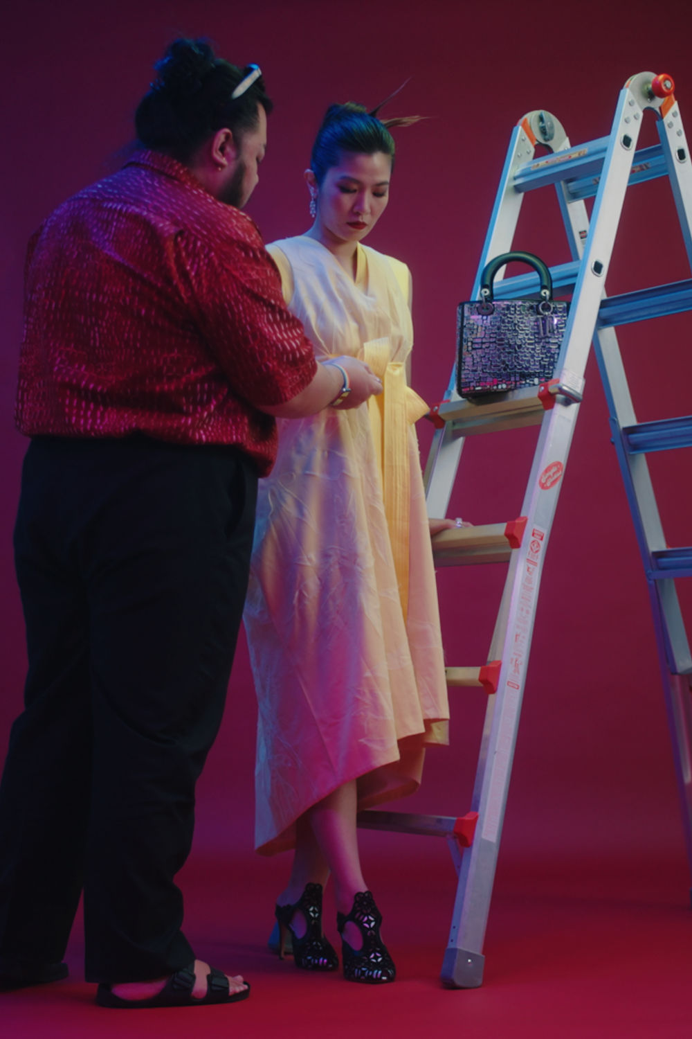 Man helping woman with the clothing for a shoot.