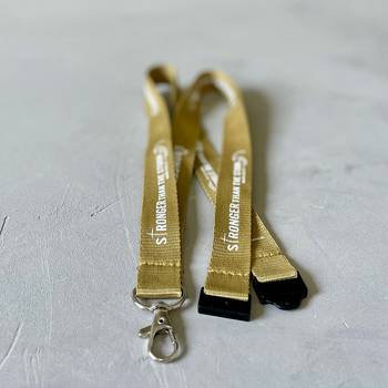 Nyckelband – Stronger, guld, en produkt från Nya Musik som utvecklar och engagerar människor i alla åldrar.