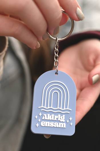 Nyckelring i silikon: Aldrig ensam, en produkt från Nya Musik som utvecklar och engagerar människor i alla åldrar.