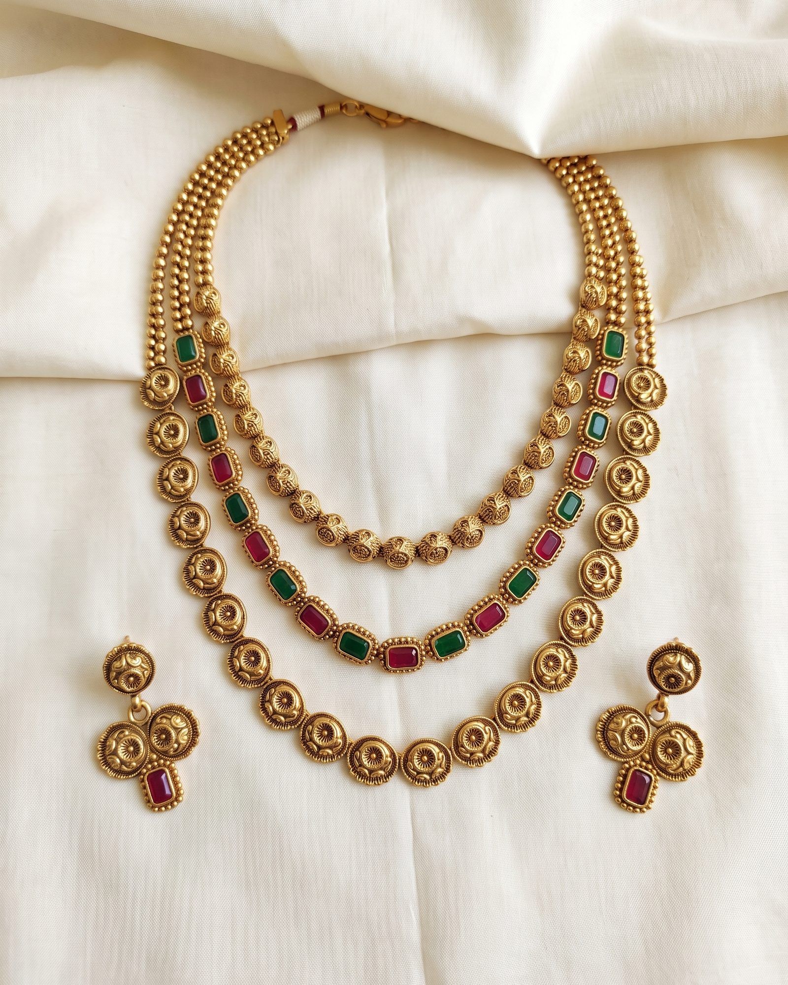 Antique Red Green Stone Disc Layered Necklace laid on white marble