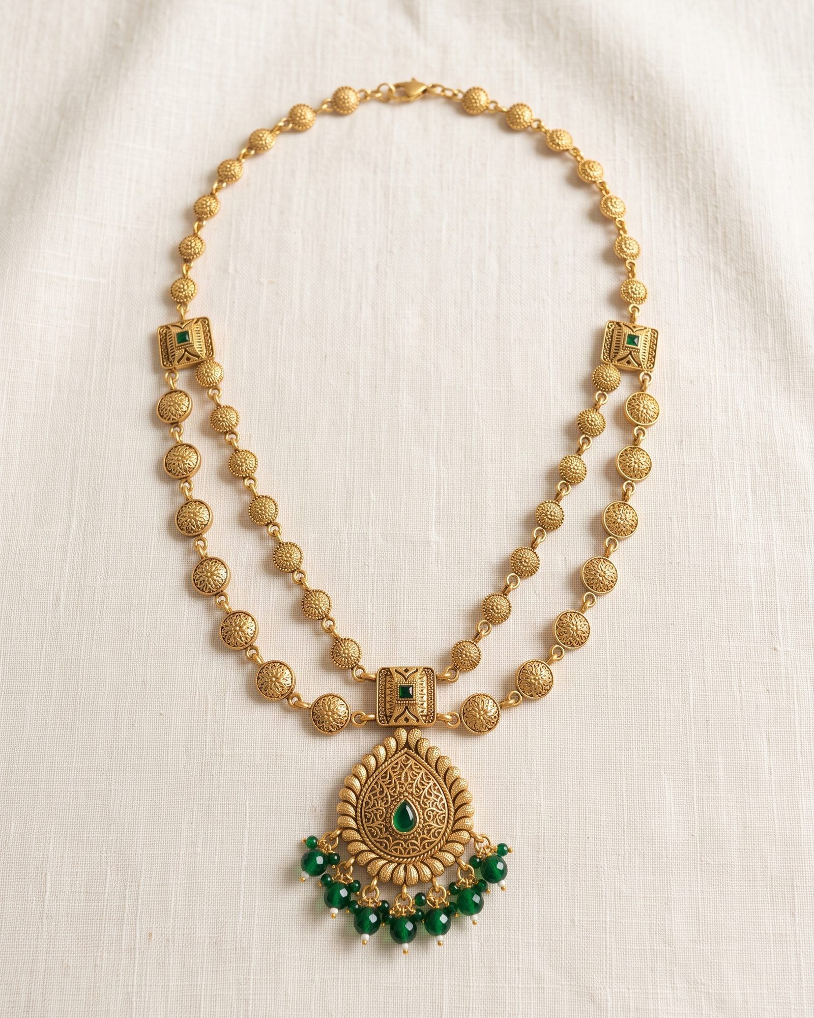 Antique Green Stone Paisley Layered Necklace laid on white marble