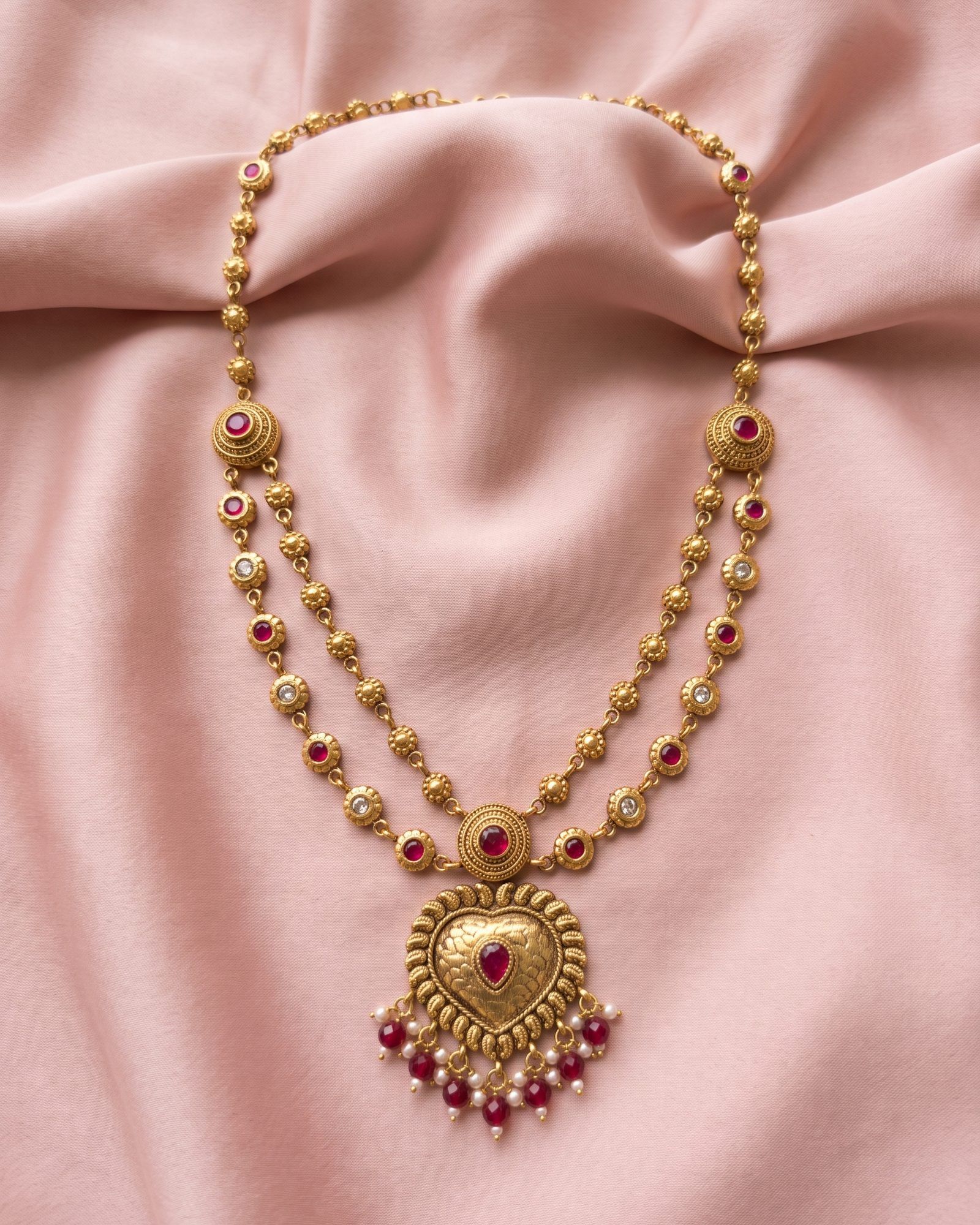 Antique Red Stone Heart Layered Necklace laid on white marble