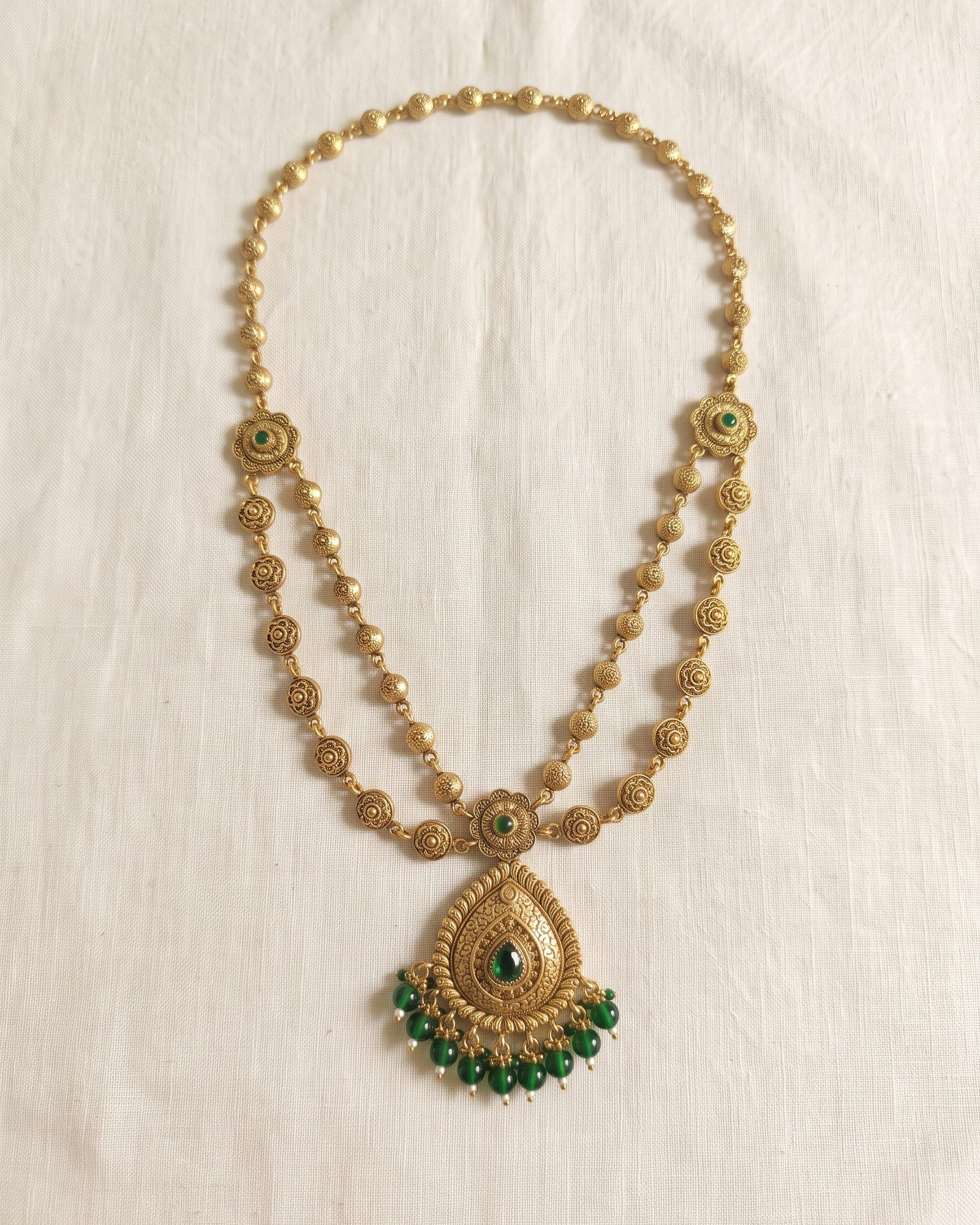 Antique Green Bead Teardrop Layered Necklace laid on white marble