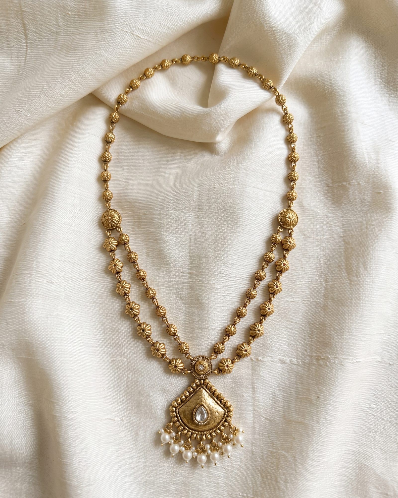 Antique Pearl Drops Pendant Layered Necklace laid on white marble