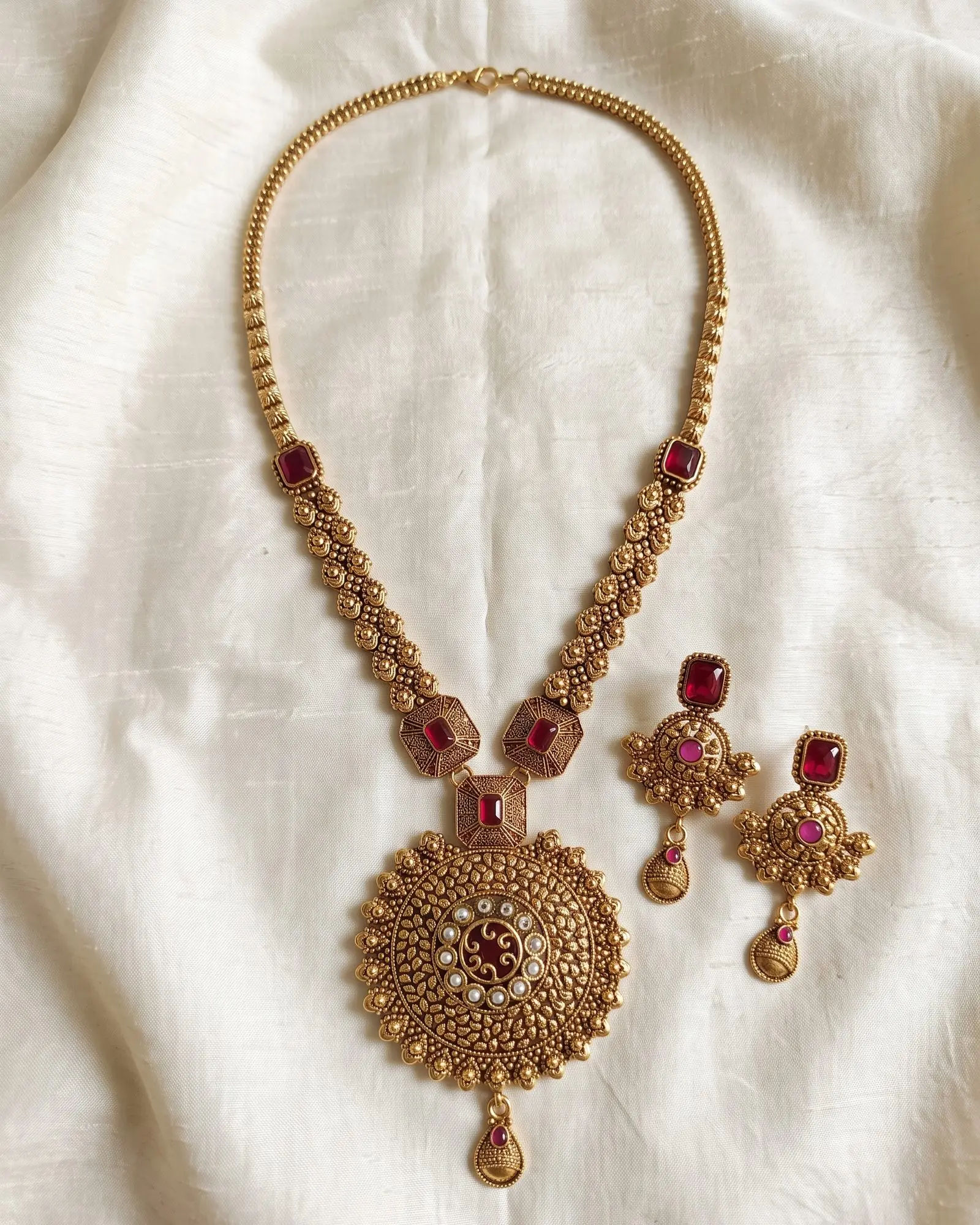 Antique Floral Red Stone Long Necklace with Earrings laid on white marble