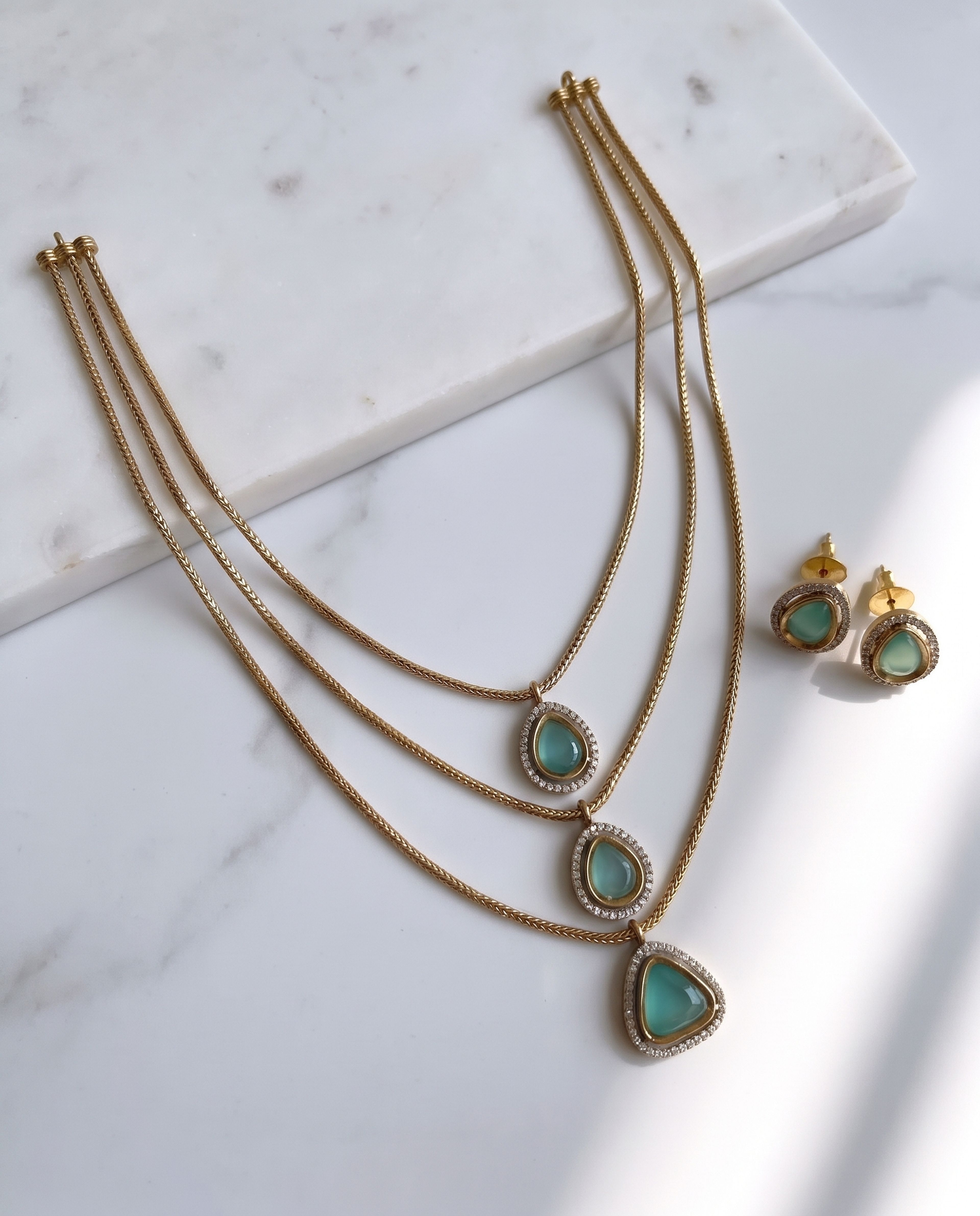 Emerald Teardrop Layer Necklace laid on white marble