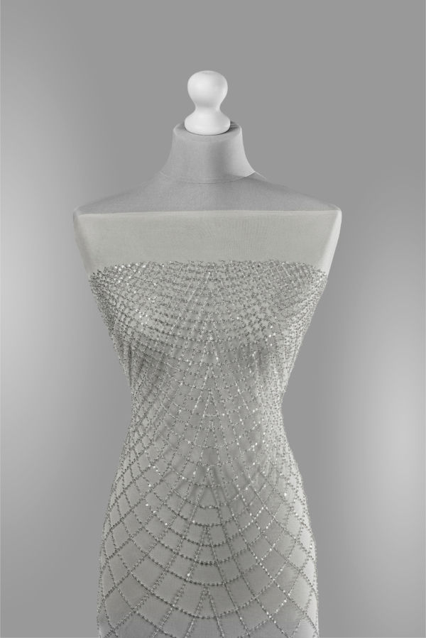 Srebrny tiul na manekinie z błyszczącym wzorem pajęczej sieci wysadzanym cekinami