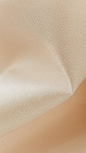 Zbliżenie gładkiej, cielistej satyny z delikatnym połyskiem i miękkim ułożeniem