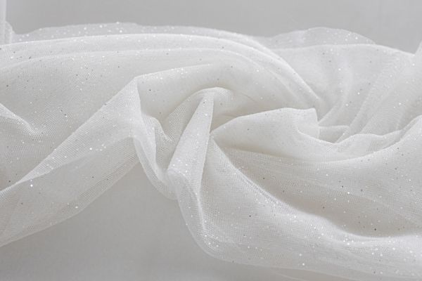 Biały tiul z drobnymi, srebrnymi drobinkami brokatu, ułożony w miękkie fałdy
