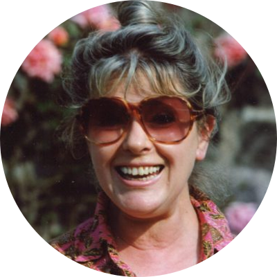 Portrait of Suzanne Rappaport Ripton smiling in a pink patterned blouse.