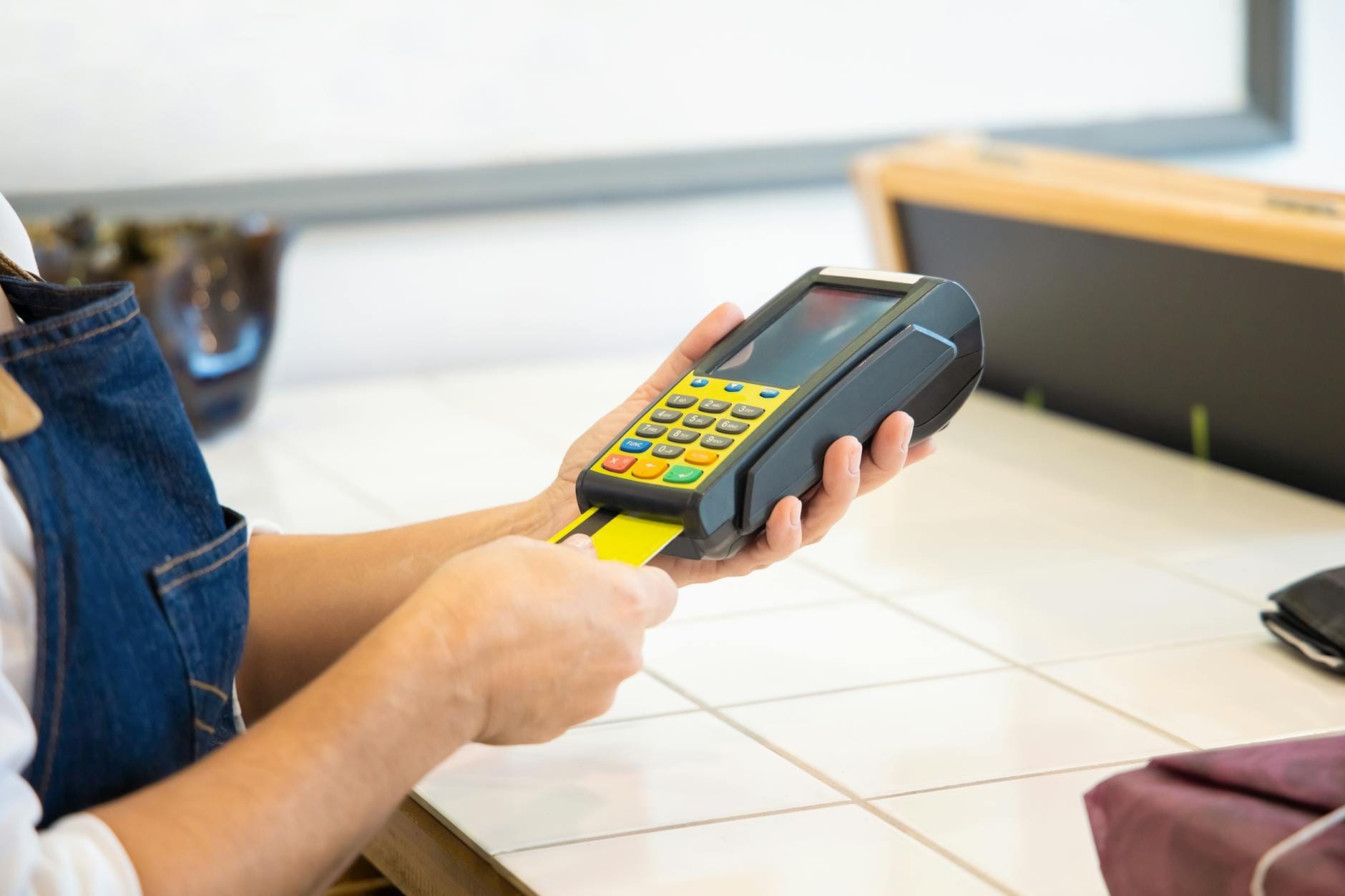 Butiksägare vid kassaterminal och laptop som visar orderflöde mellan kassa och webbutik efter integration.
