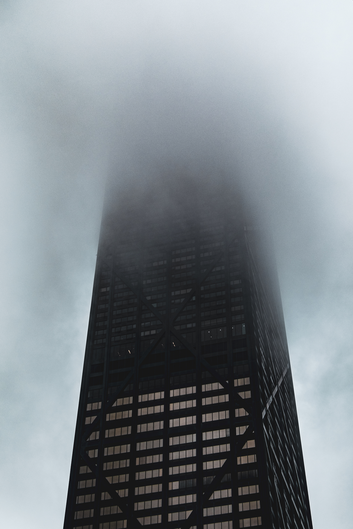 Tall black skyscraper disappearing into rain clouds.