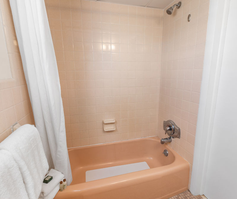 A pink bathtub with tiled walls and a shower curtain