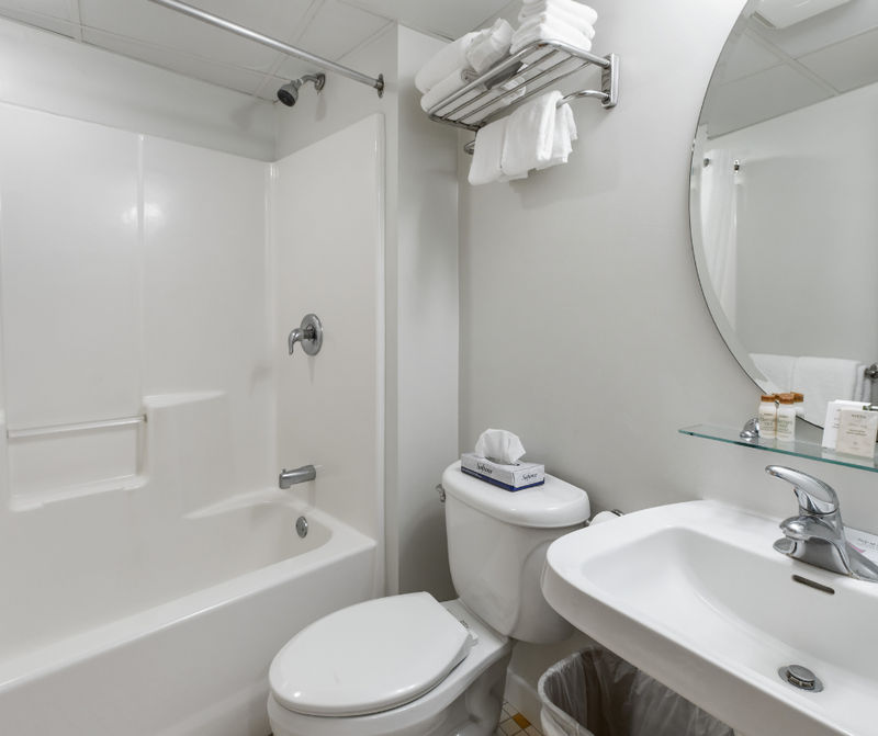 A standard hotel bathroom with a bathtub, toilet, sink, and mirror.