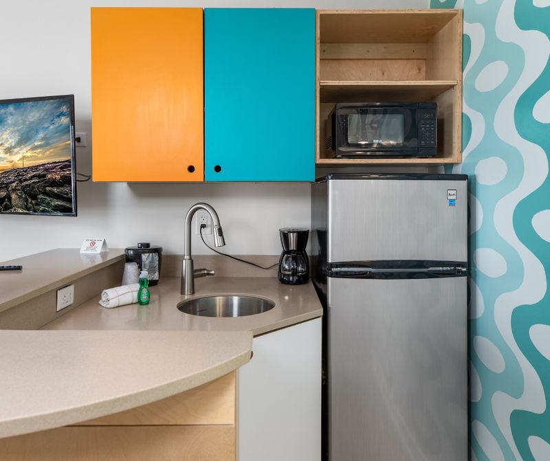 A compact kitchenette with a sink, refrigerator, microwave, and coffee maker.