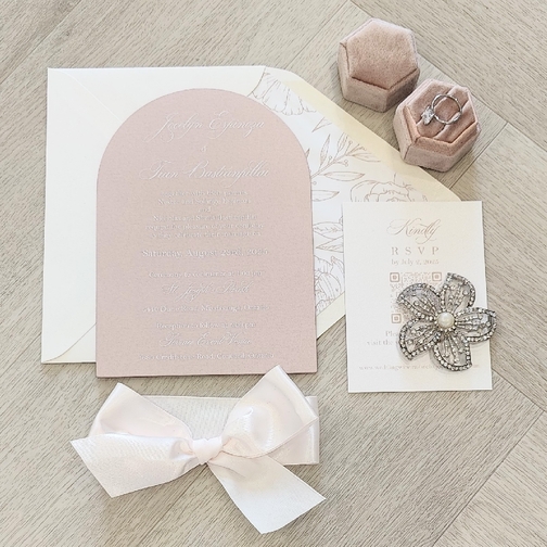 Arch shaped invitation with an antique ivory ribbon bow.  Neutral envelope with a printed floral design liner.