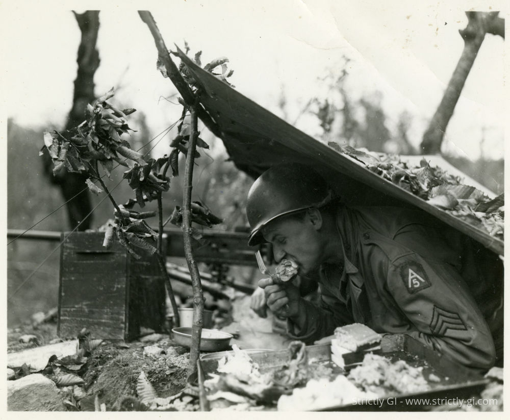 Thanksgiving chow went as far forward as there were troops. Sergeant Frank Shiborski, 107th Anti-Aircraft Artillery Group, from 5007 Central Avenue, Detroit, Michigan, a 50 Cal. Machine Gunner, takes time out from looking for Germans to do a little special duty on a drum stick somewhere near San Marcello Pistoiese, Italy.