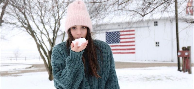 Exchange Student con neve in mano e bandiera USA sullo sfondo.