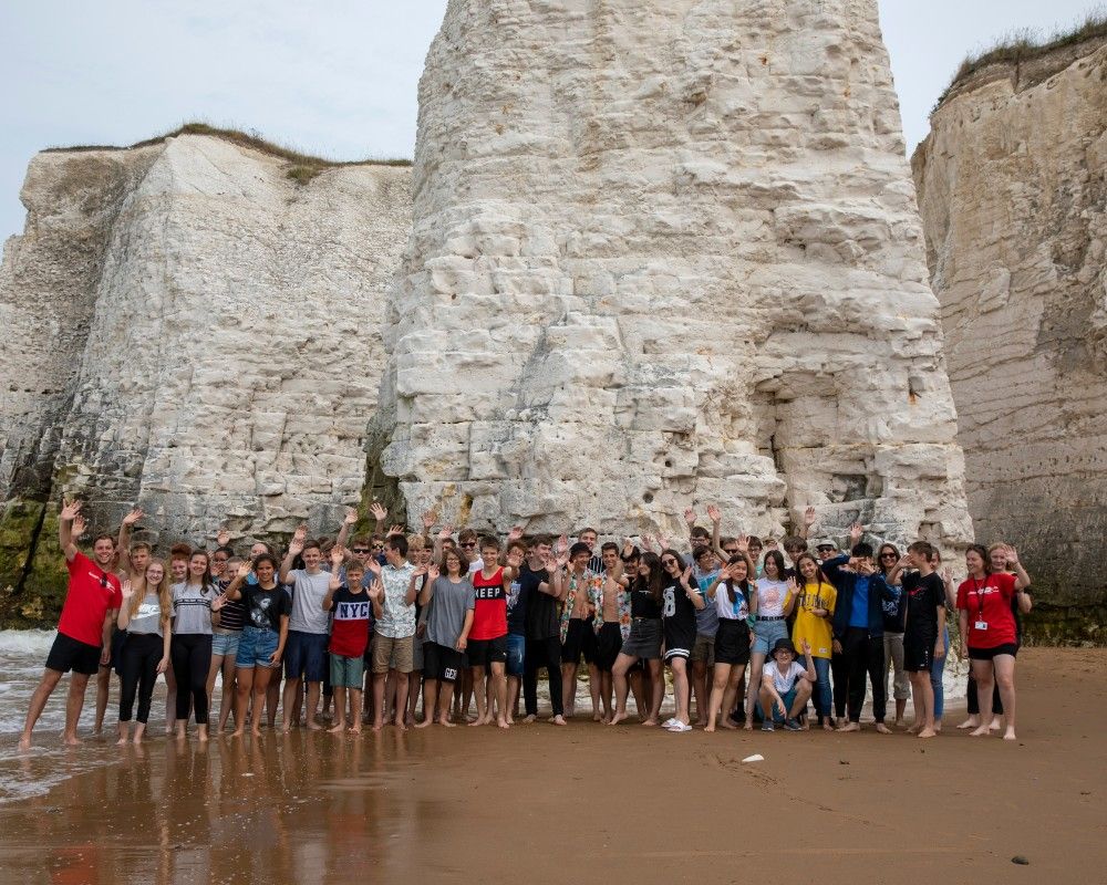 Numerosi ragazzi in posa davanti alle scogliere bianche della Kingsgate Bay Beach
