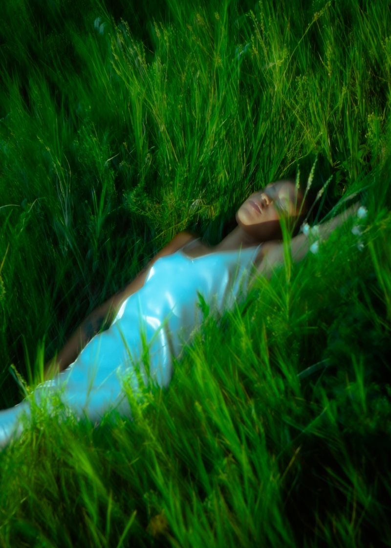 photo of a person in a dress lying in a lush bed of grass