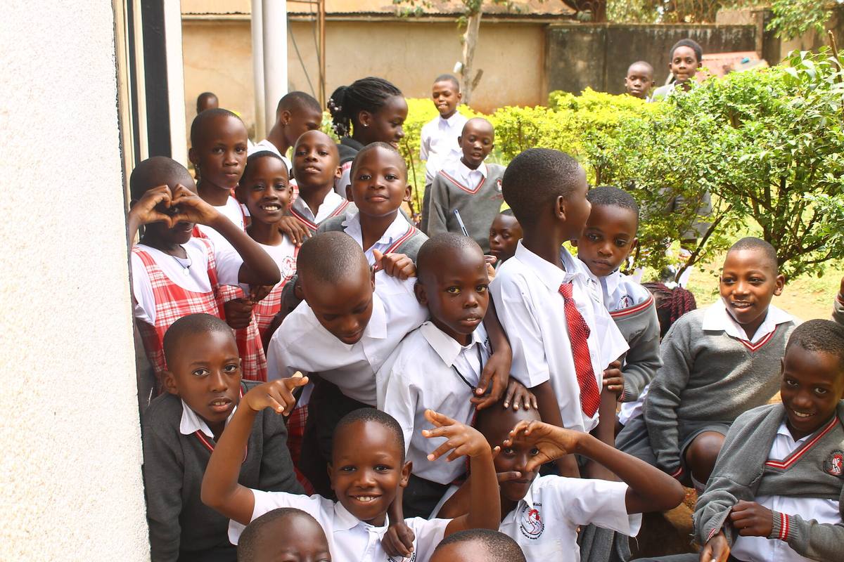 A crowd of smiling pupils in uniform posing outside their classroom