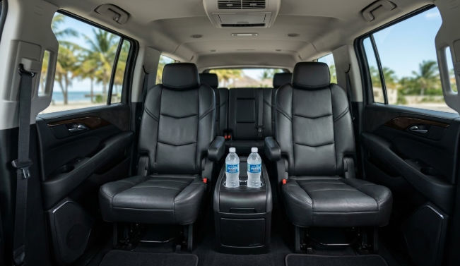 A happy couple with luggage walking towards a white passenger van with the door open at a luxury Cancun resort.