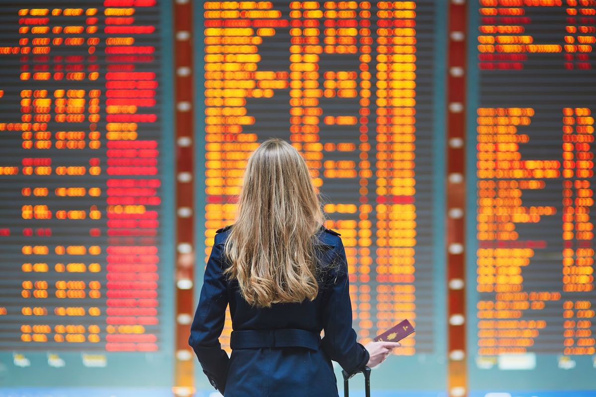 La mujer llegó tarde a su vuelo de conexión y mira la pantalla de salidas en el aeropuerto.