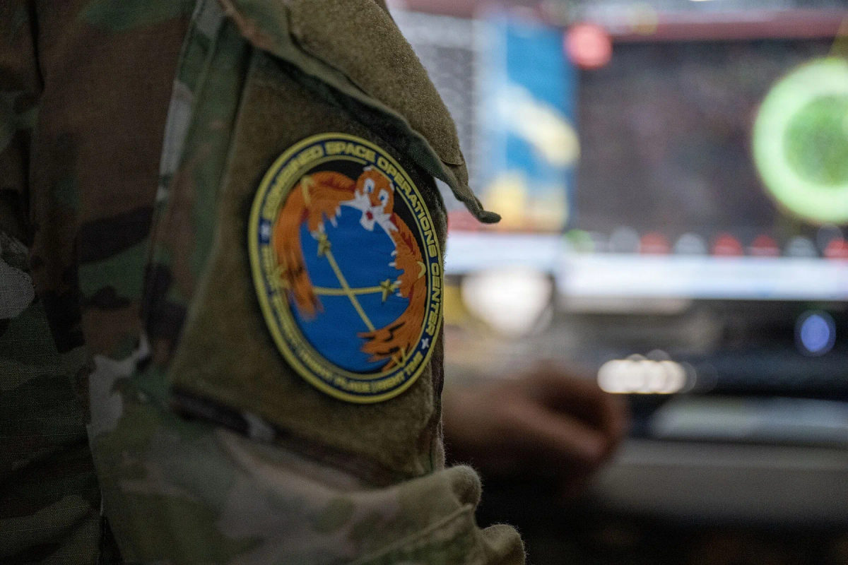 A uniformed operator works at a multi-monitor workstation.