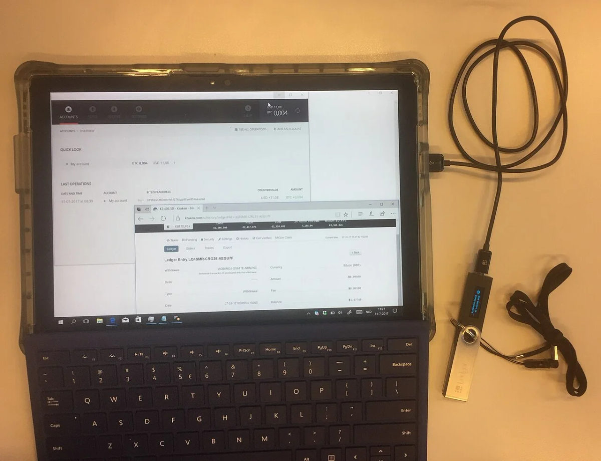 A Bitcoin transaction from Kraken displayed beside a Ledger hardware wallet.