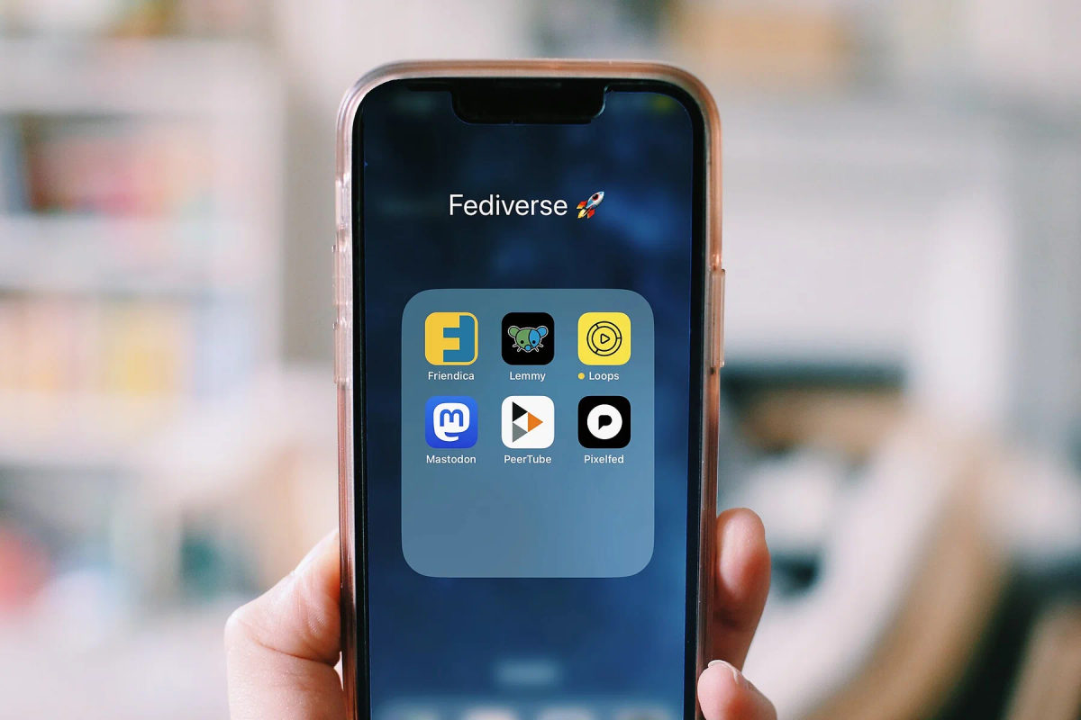 A hand holds a smartphone displaying a grid of social-media app icons.