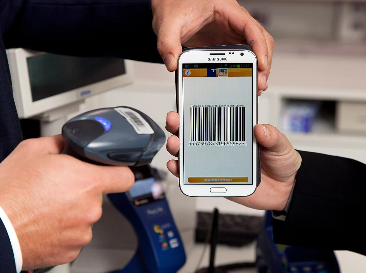 A shopper's phone barcode being scanned at a checkout.