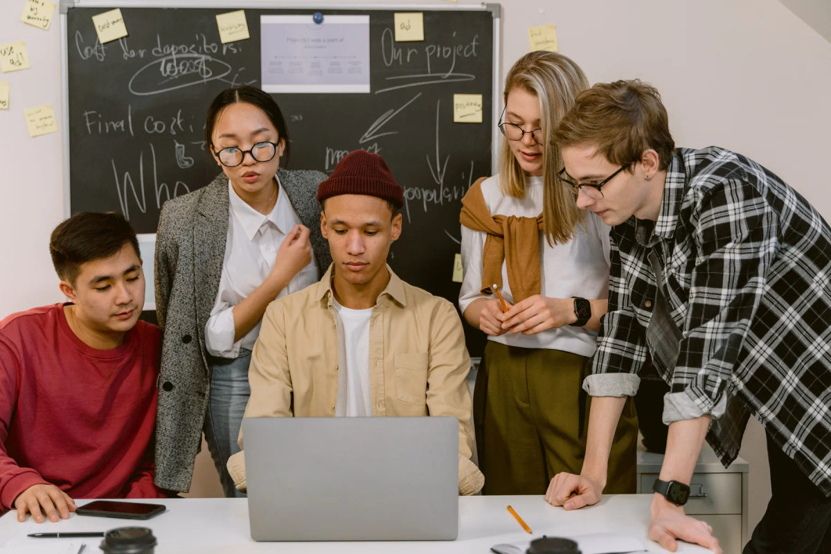 A small team reviews ideas around a laptop in an office.