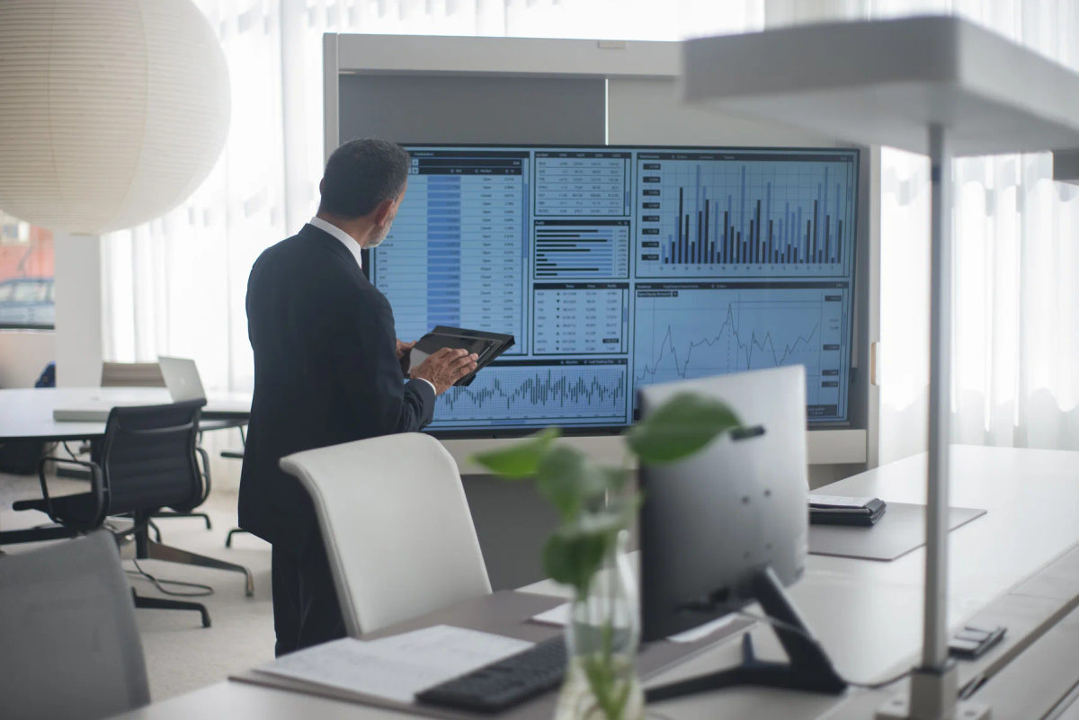 A professional reviews financial data on screens in an office.