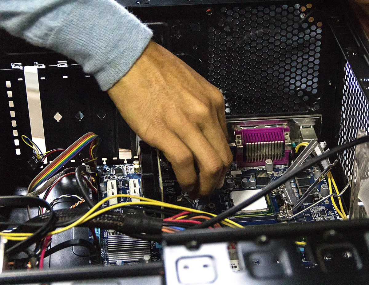 A person works on an open computer during maintenance.