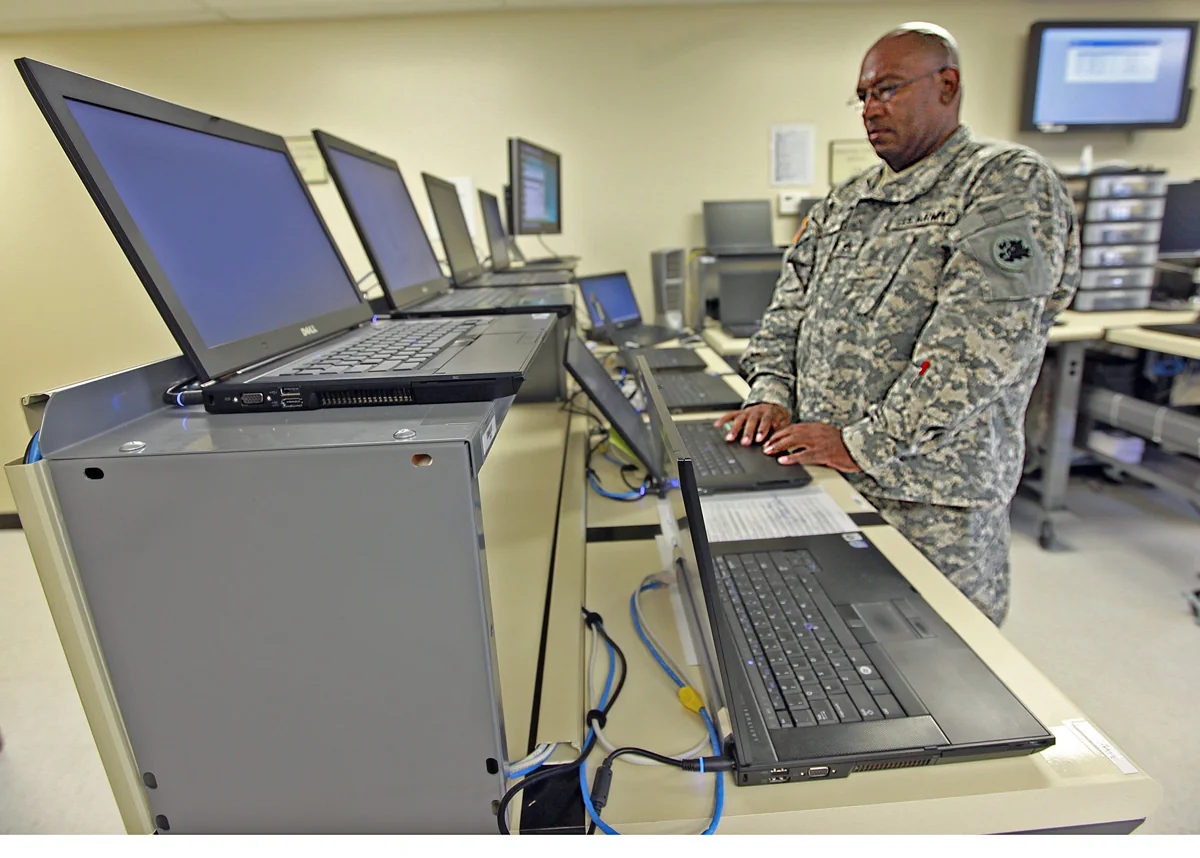 A technician repairs a laptop at a desk.
