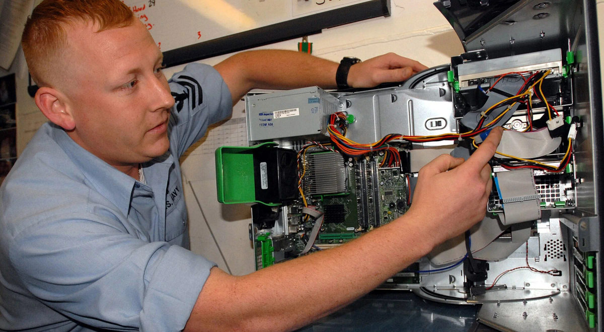 A technician inspects the internal parts of a desktop computer.