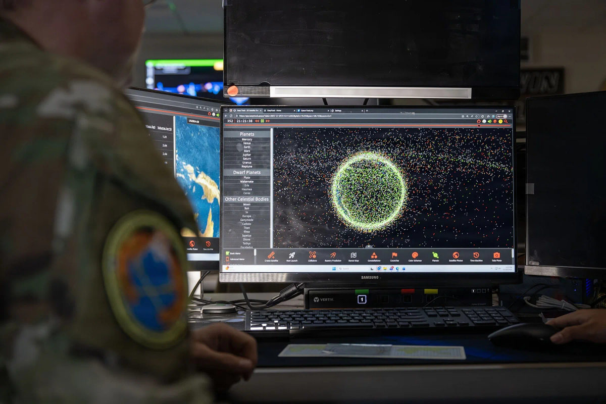A uniformed operator works at a multi-monitor workstation.