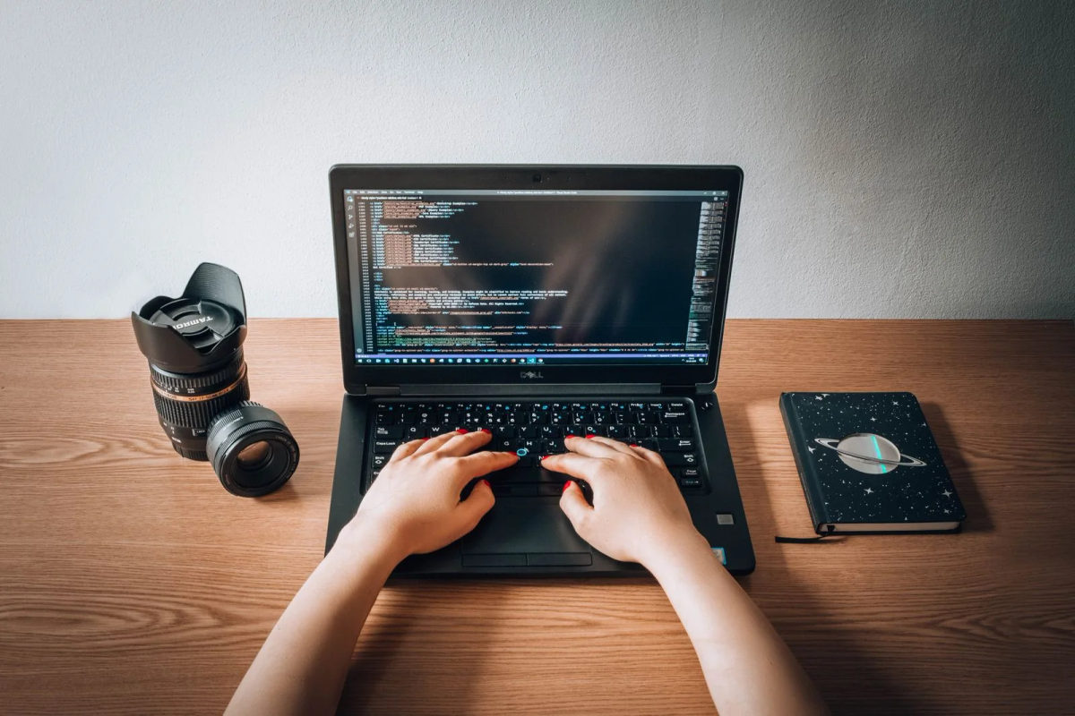 A woman coding on a laptop in a home office.