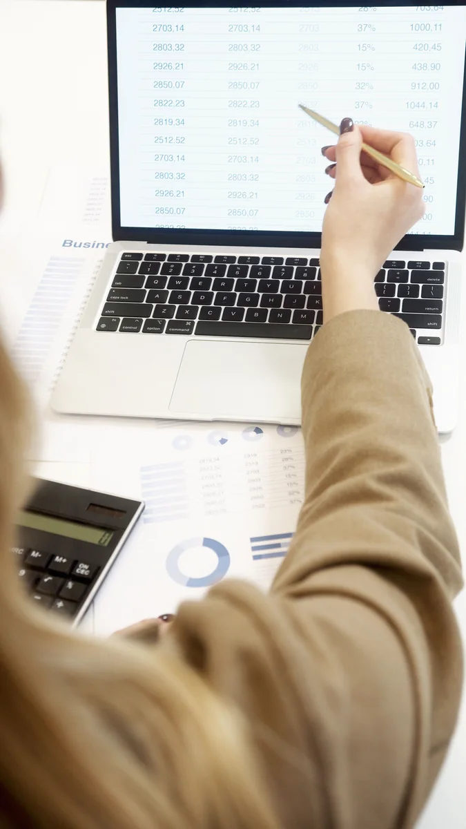 A business professional analyzes financial data on a laptop.