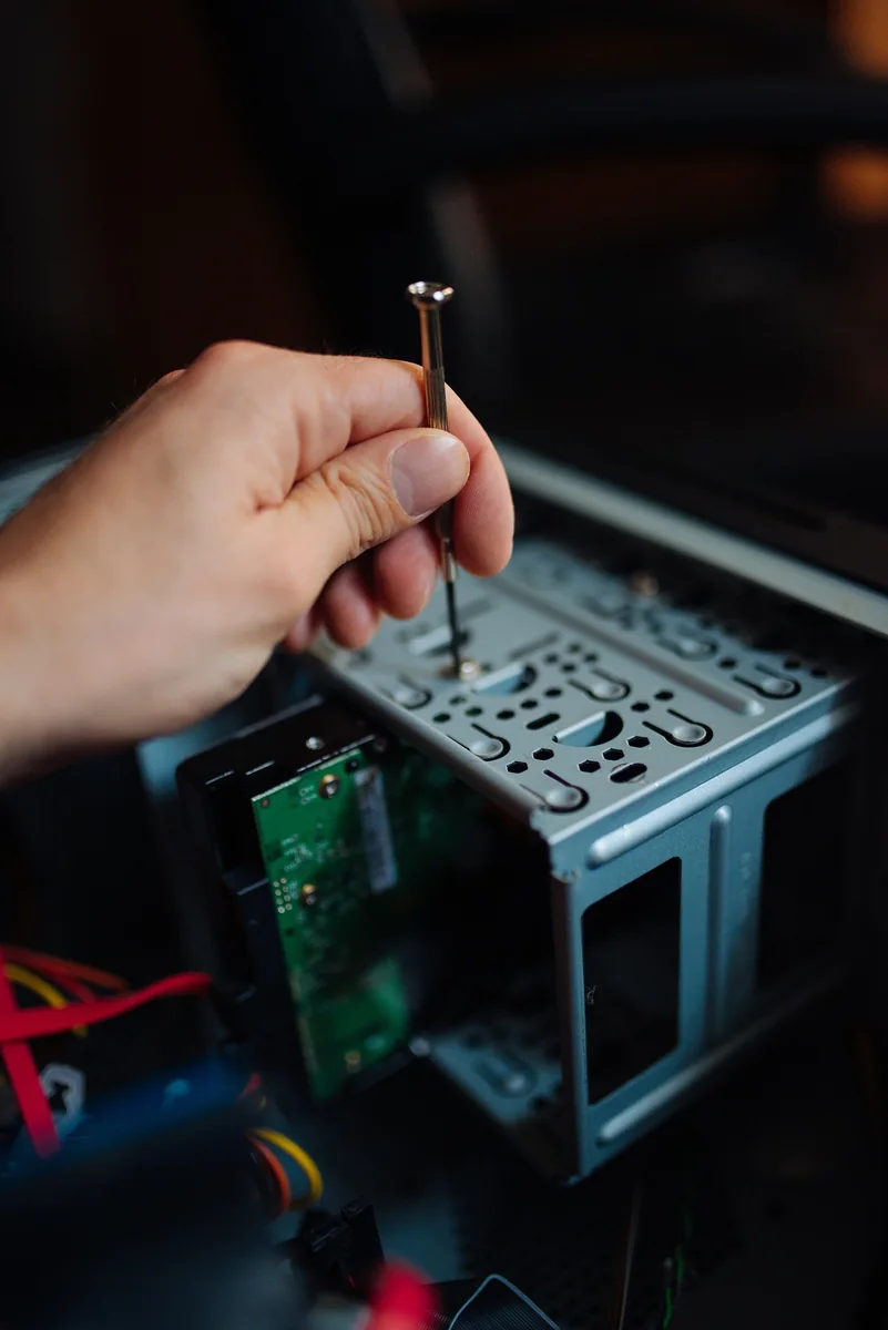 A person removes a hard drive from an open desktop computer.