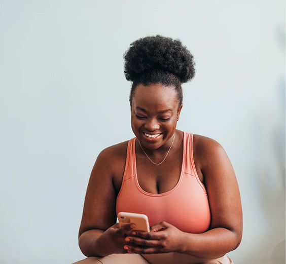 A smiling Lean Meds member checking her weight-loss progress on her phone