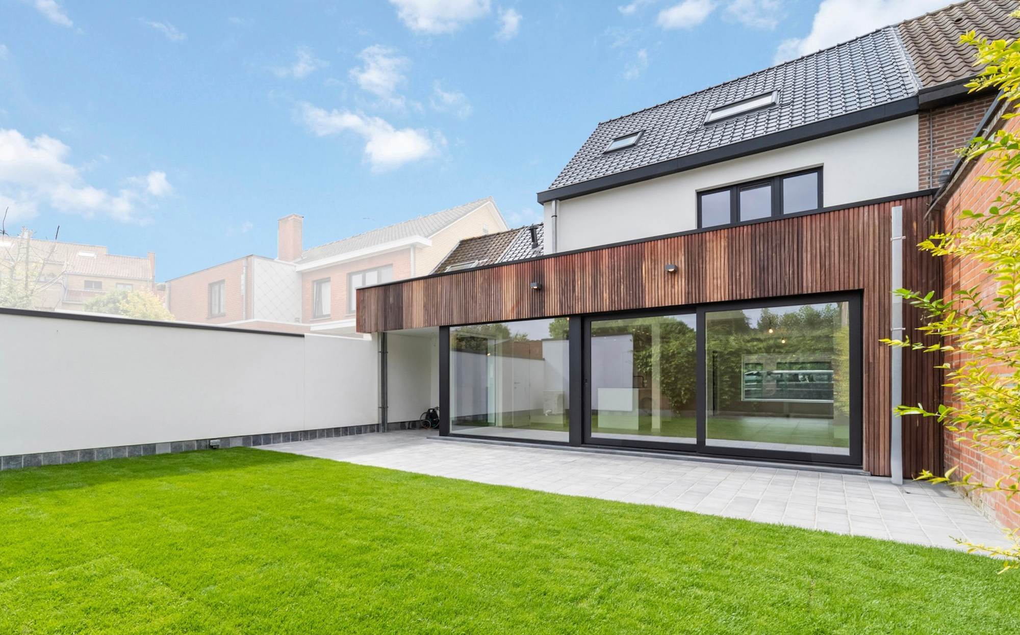 Totaalgerenoveerde woning in Oostkamp met witte gevel en een band verticale houten latten