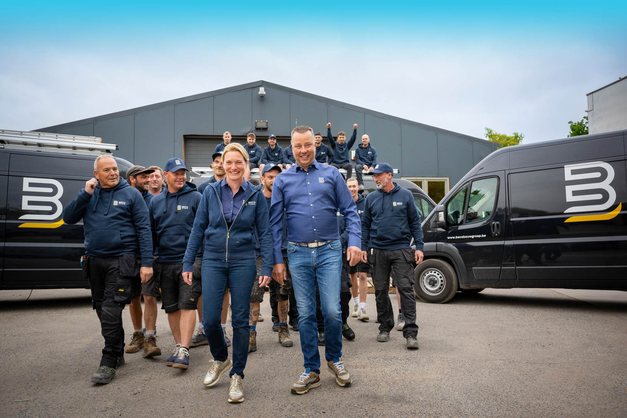 De ploeg van Beco Bouwgroep loopt tussen twee bestelwagens naar de camera toe